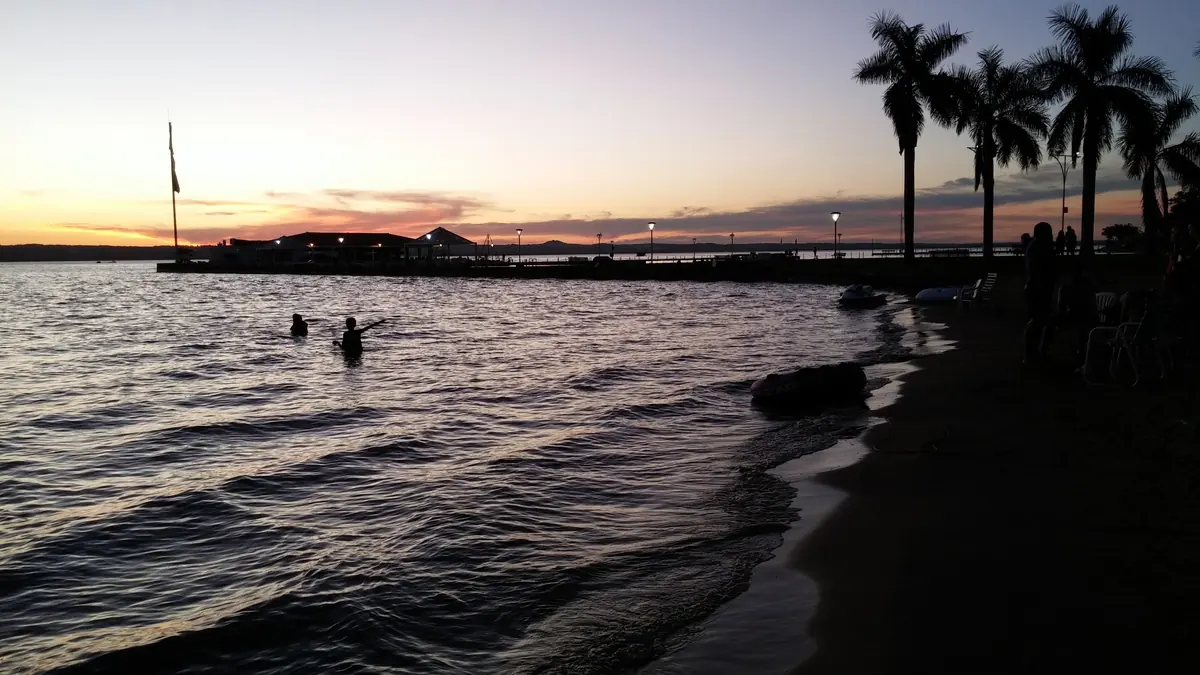 Atardecer sobre el lago Ypacaraí, con palmeras en la orilla